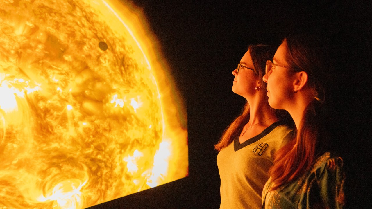 Two people looking at an upclose solar image on a digital screen.