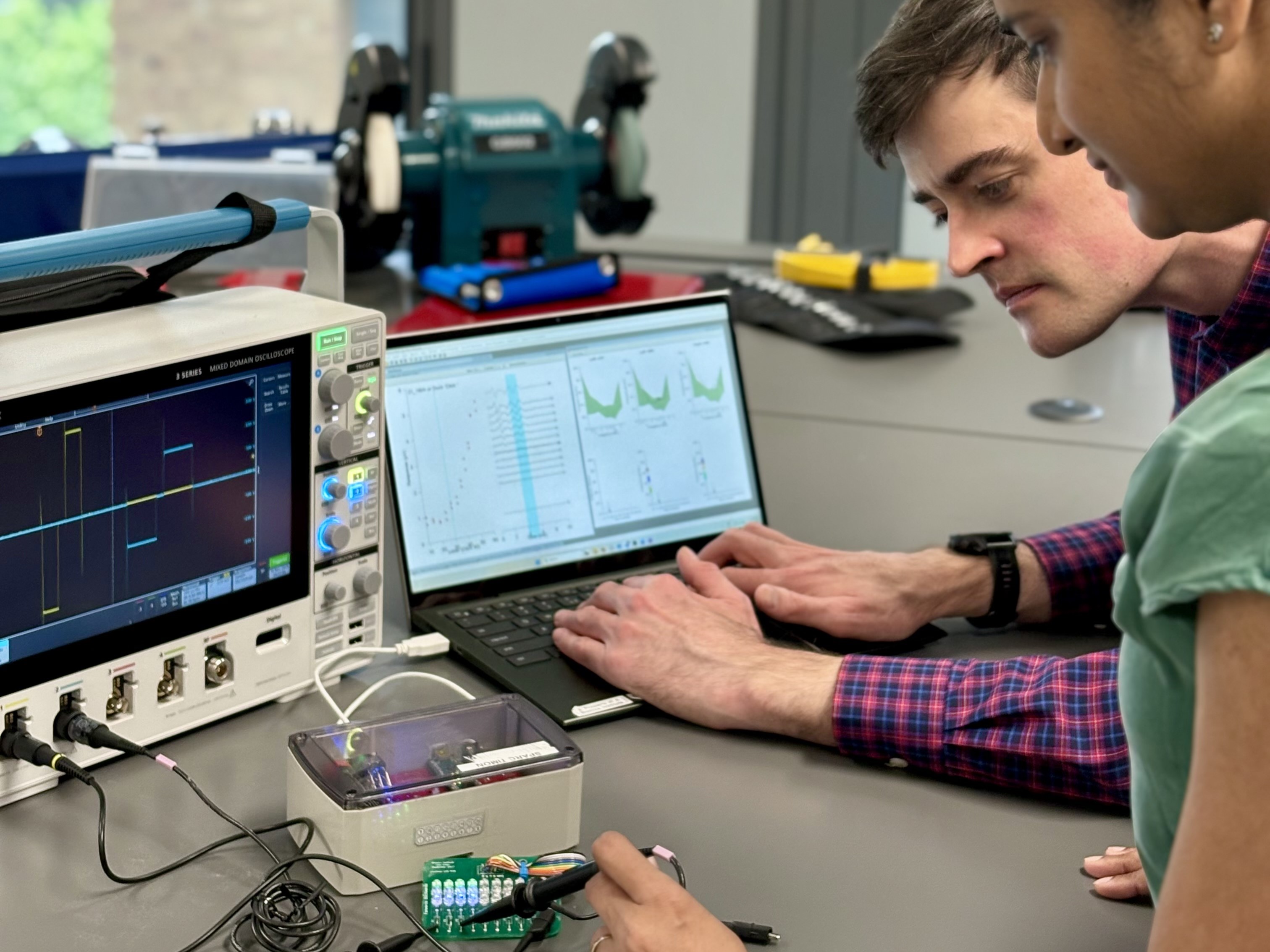 A man and woman look over computer data and tinker with electronics