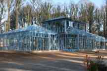 Blue steel frame of semi constructed house with large trees in the background