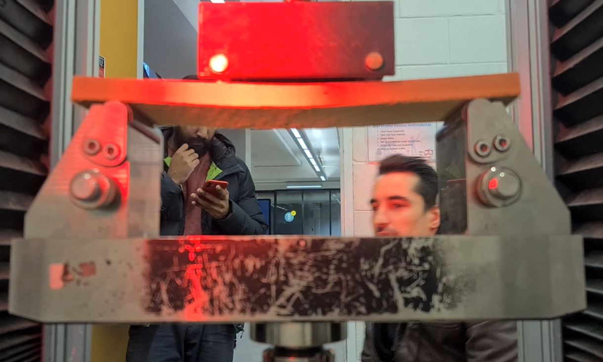 Daniel Prohasky watches on as an oversized metal clamp applies force to testing material 