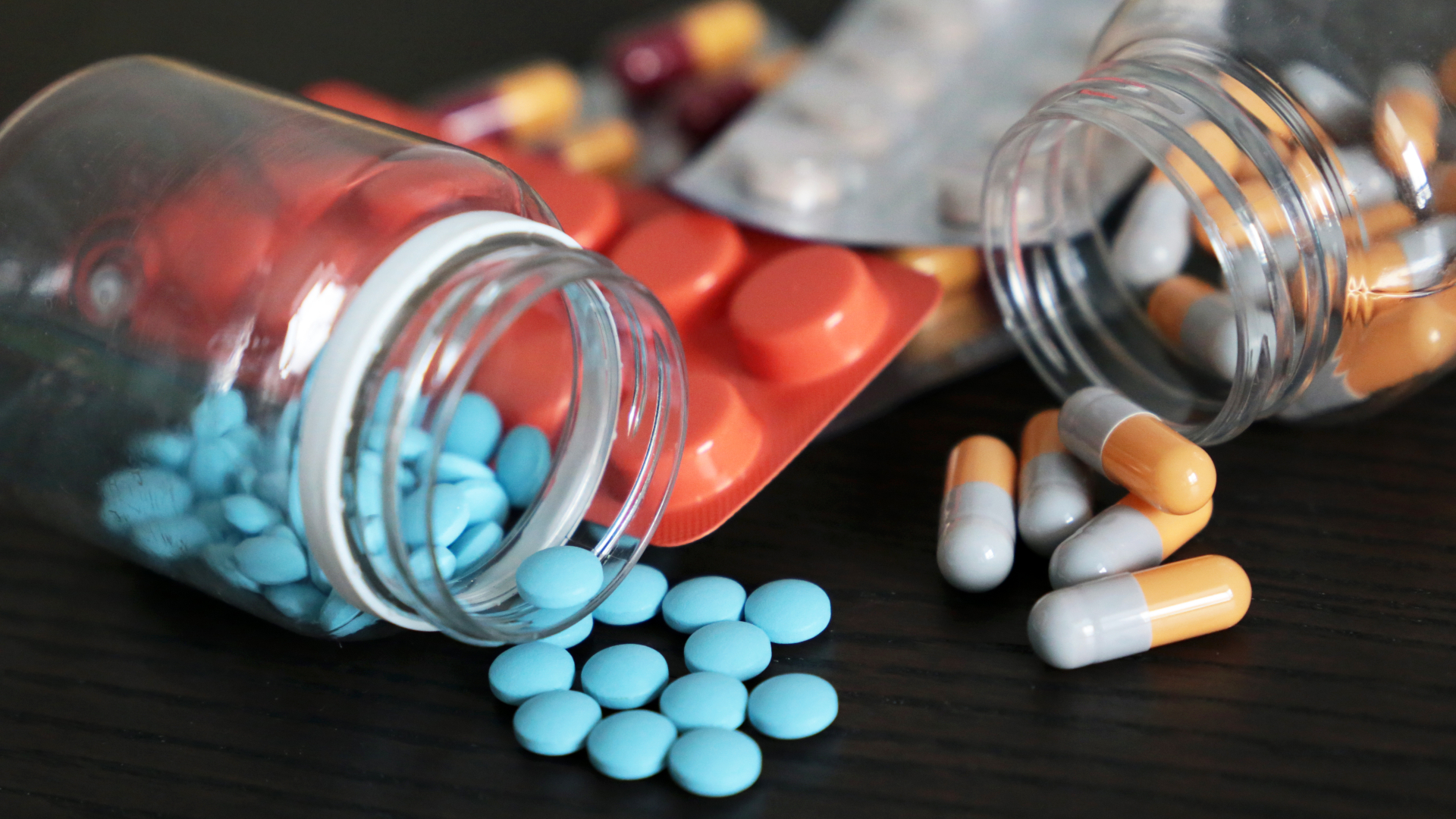 Pills and capsules on dark wooden table