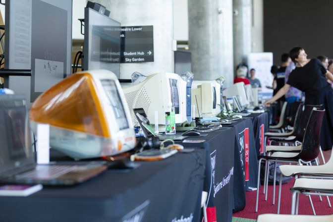A table with rows of old computers being emulated onto modern laptops.