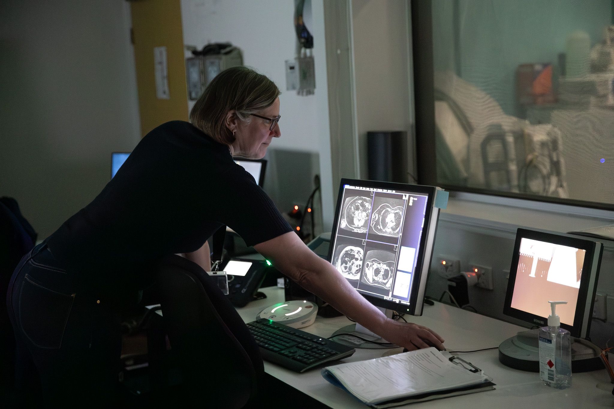 A woman uses a mouse to scroll through MRI scan data, shown on screen as a cross-section of a human body, inside the Swinburne Neuroimaging facility.