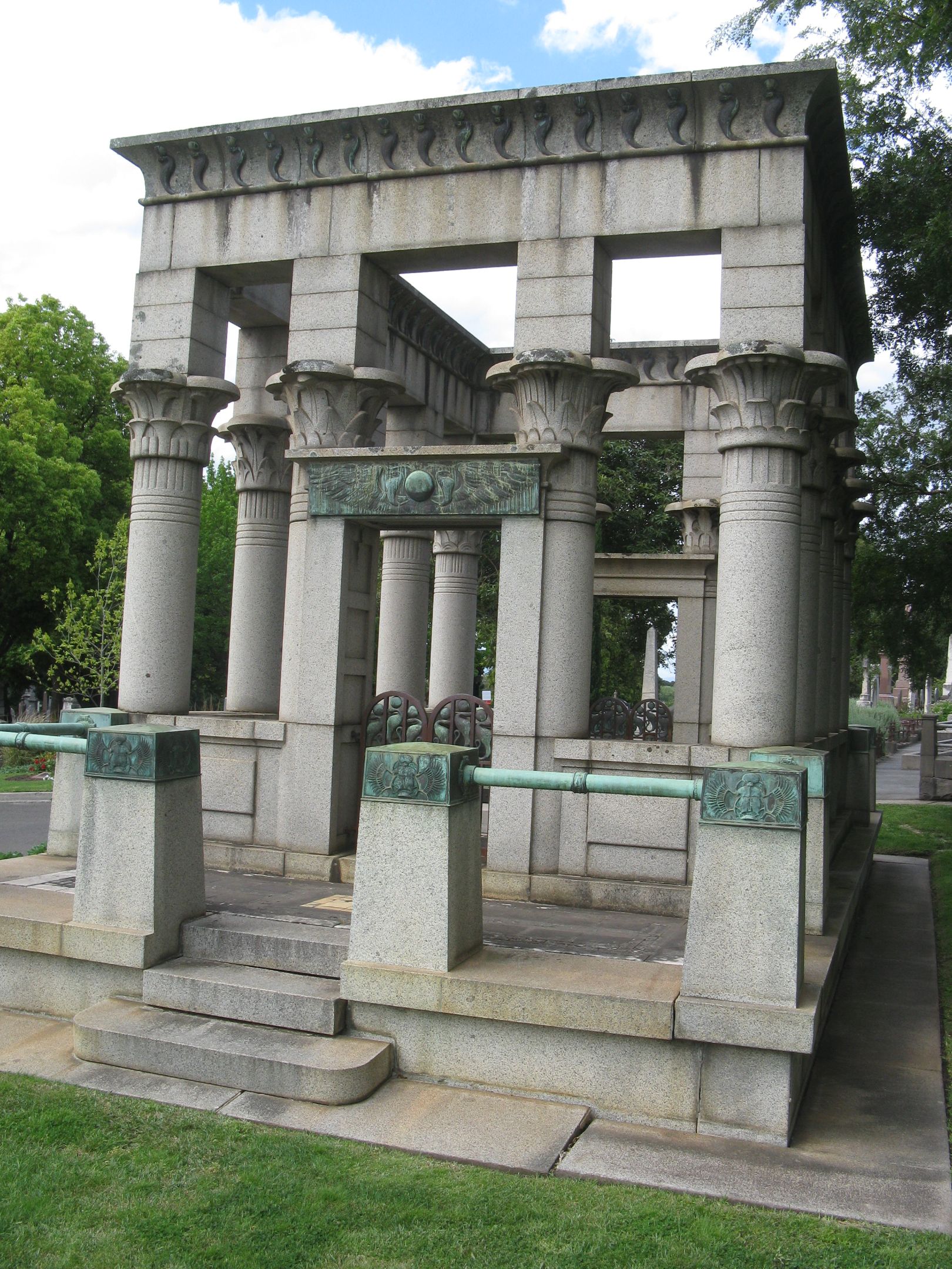 A memorial made out of multiple stone or granite columns, sitting in a cemetary. 
