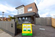 Two-storey home with sign in front displaying energy consumption of the home