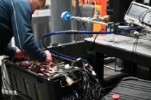 Person bends over crate of cords and other technical equipment that is a prototyping project startup company, NextAero.