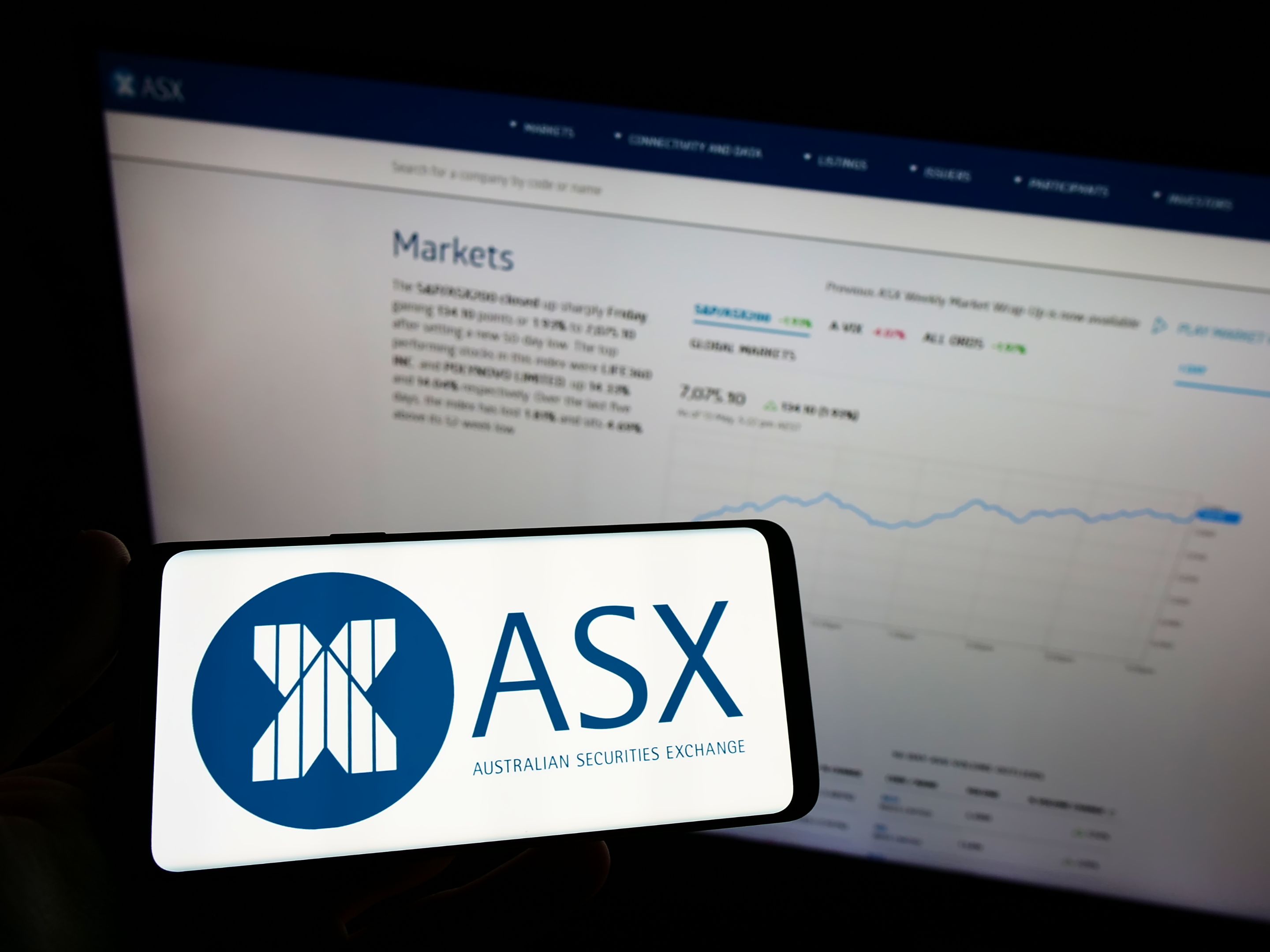 Stuttgart, Germany - 05-15-2022: Person holding mobile phone with logo of Australian Securities Exchange Ltd (ASX) on screen in front of business web page. Focus on phone display.