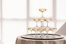 Champagne glasses stacked on top on each other to form a pyramid. 