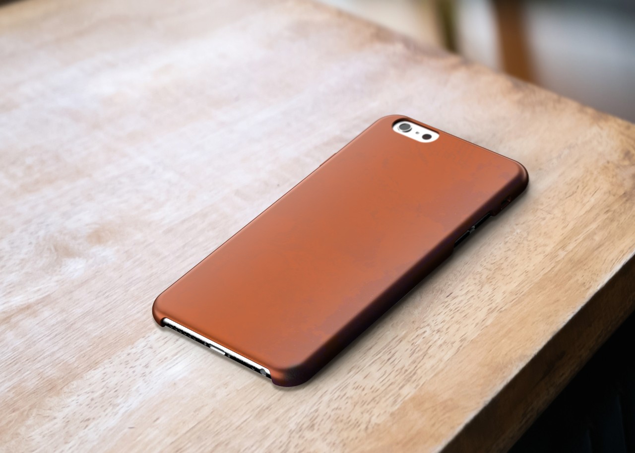A mockup of a copper phone case sitting on a wooden table, subtle wear and darkening of colour