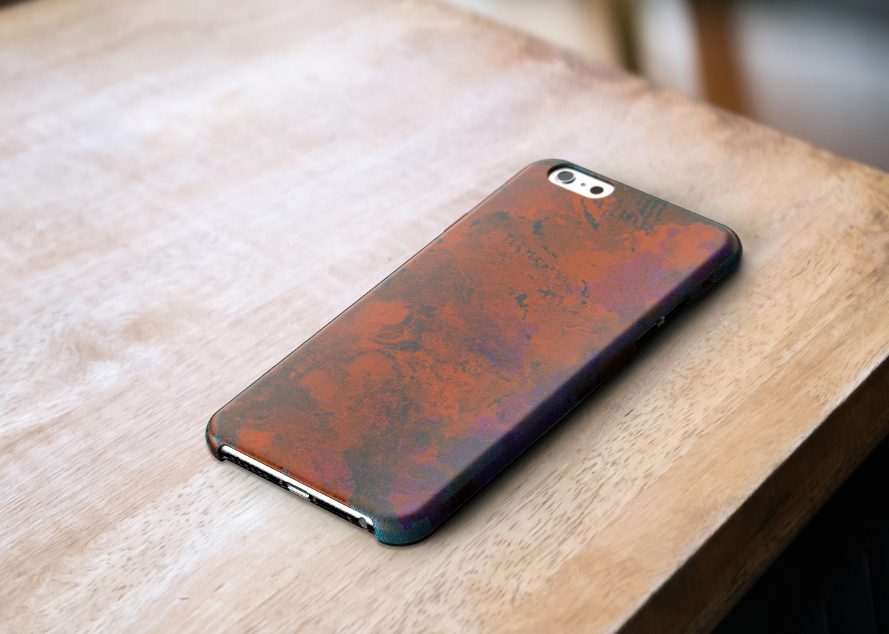 A mockup of a copper phone case sitting on a wooden table, very heavy wear and darkening