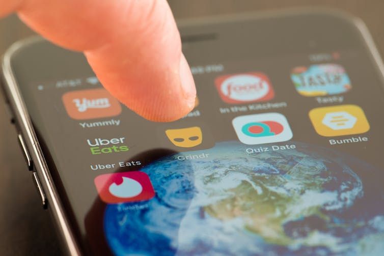 A finger about to press the Grindr app on a iPhone