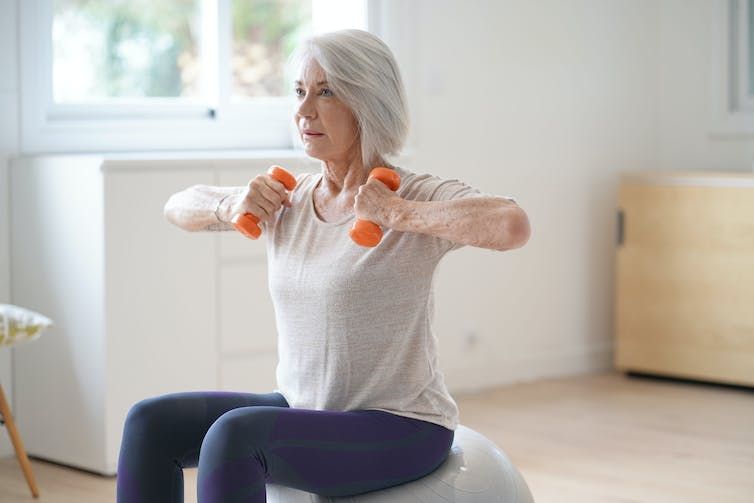 Women sitting on an exercise ball as she lifts dumbells