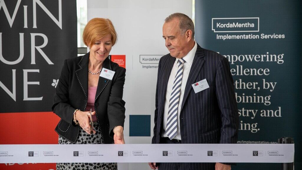 Two people cutting the ribbon at a launch event.