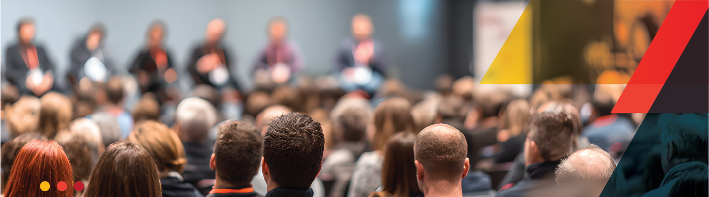 Image of an audience watching a panel discussion with abstract colour shapes to the right of the image