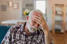Shot of a senior man with a headache holding his head while sitting on a sofa at home in the living room.