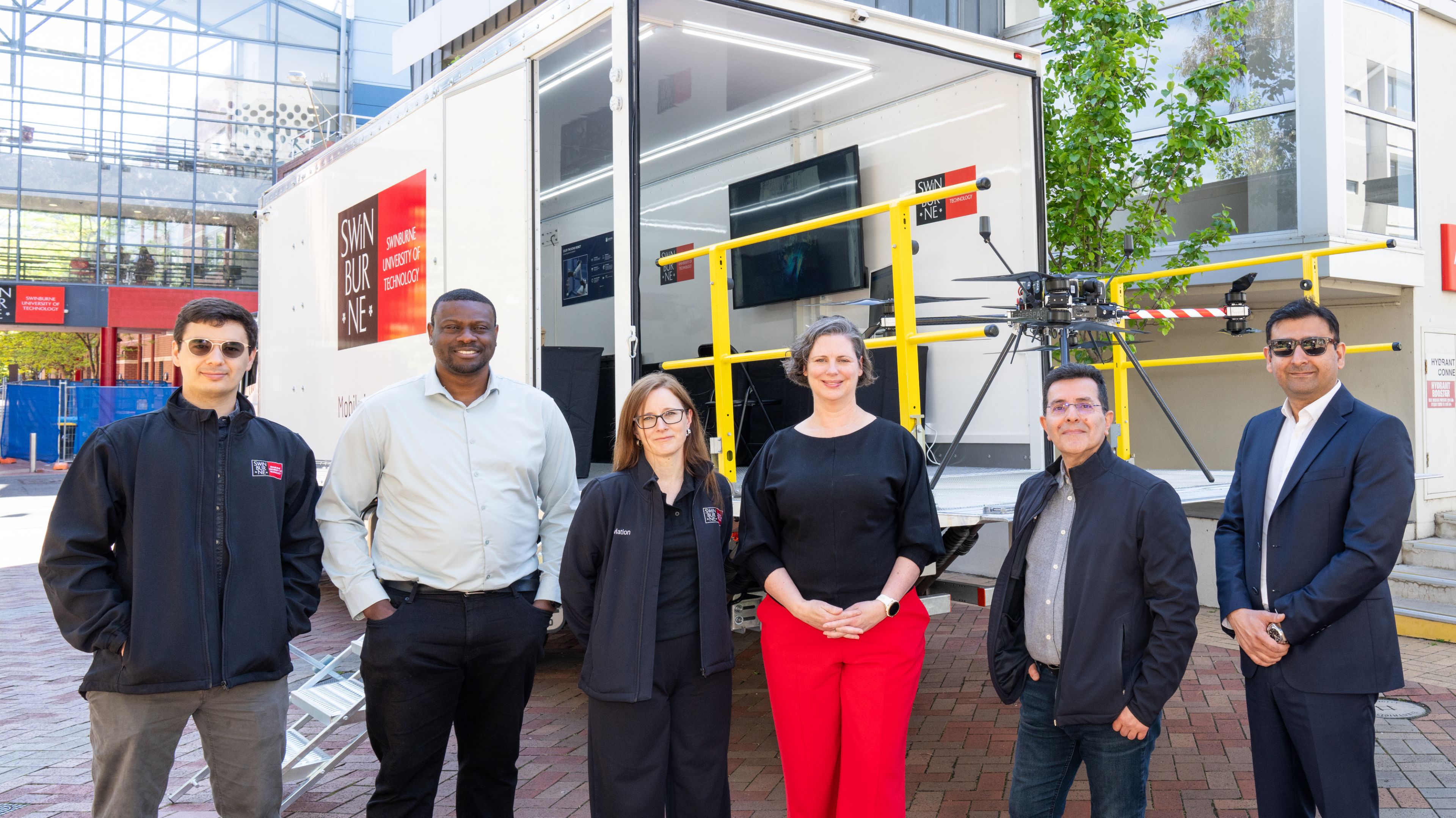 Team stands in front of a Swinburne truck with equipment and a drone.