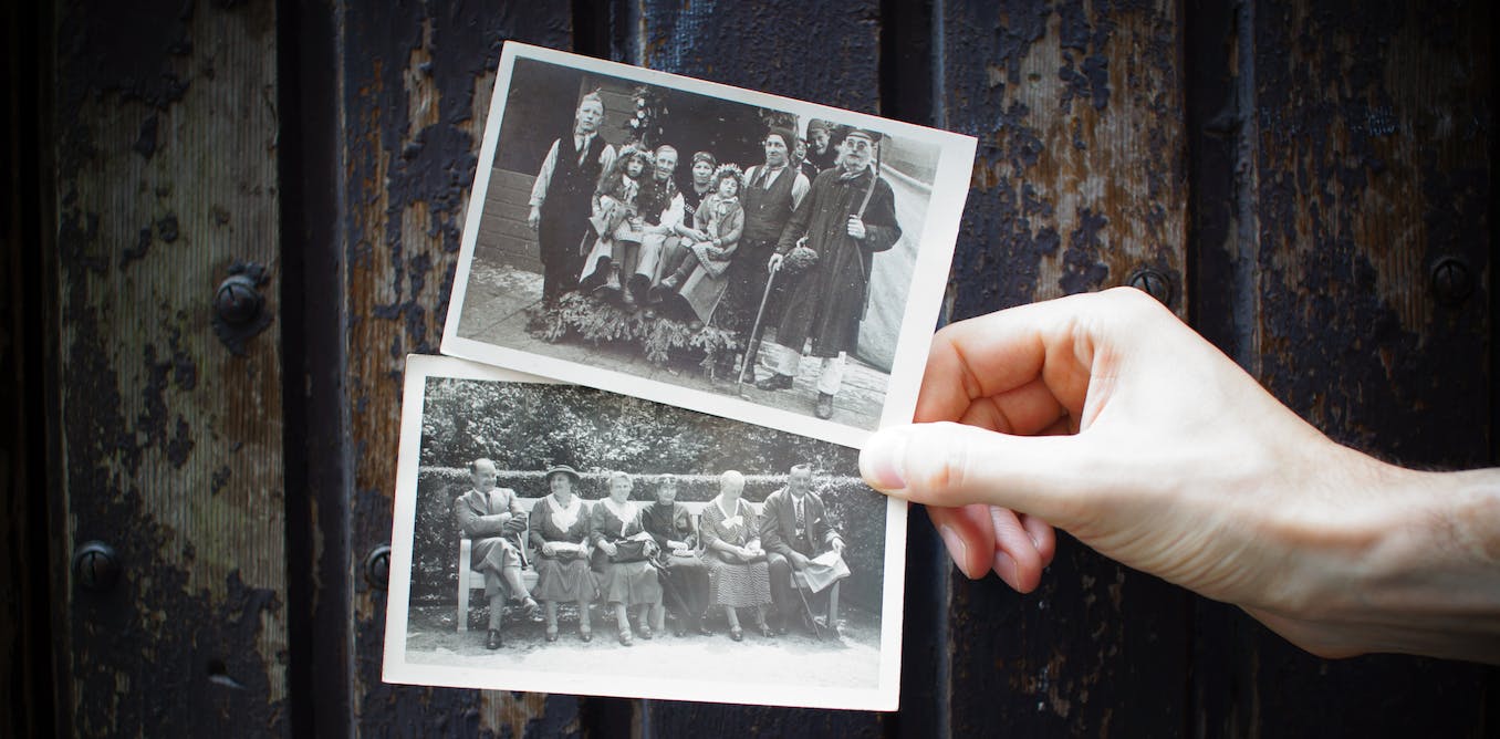 Hand holding out two black-and-white old family photos 