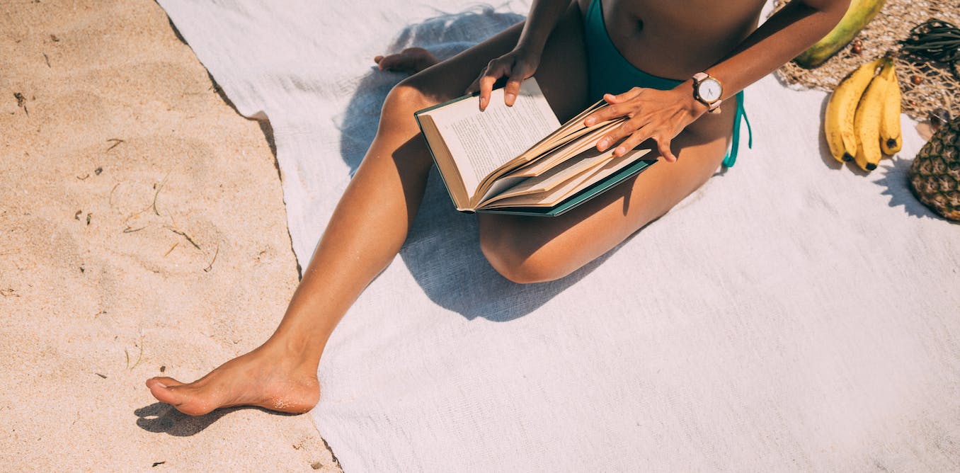Person reading a book at the beach during summer