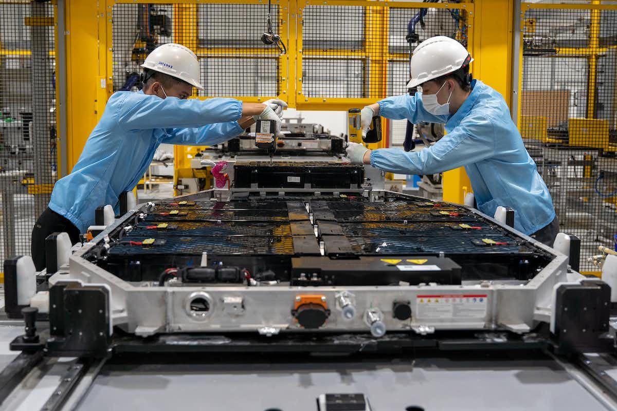 Two workers in a factory adjusting electric vehicle batteries on the assembly line 