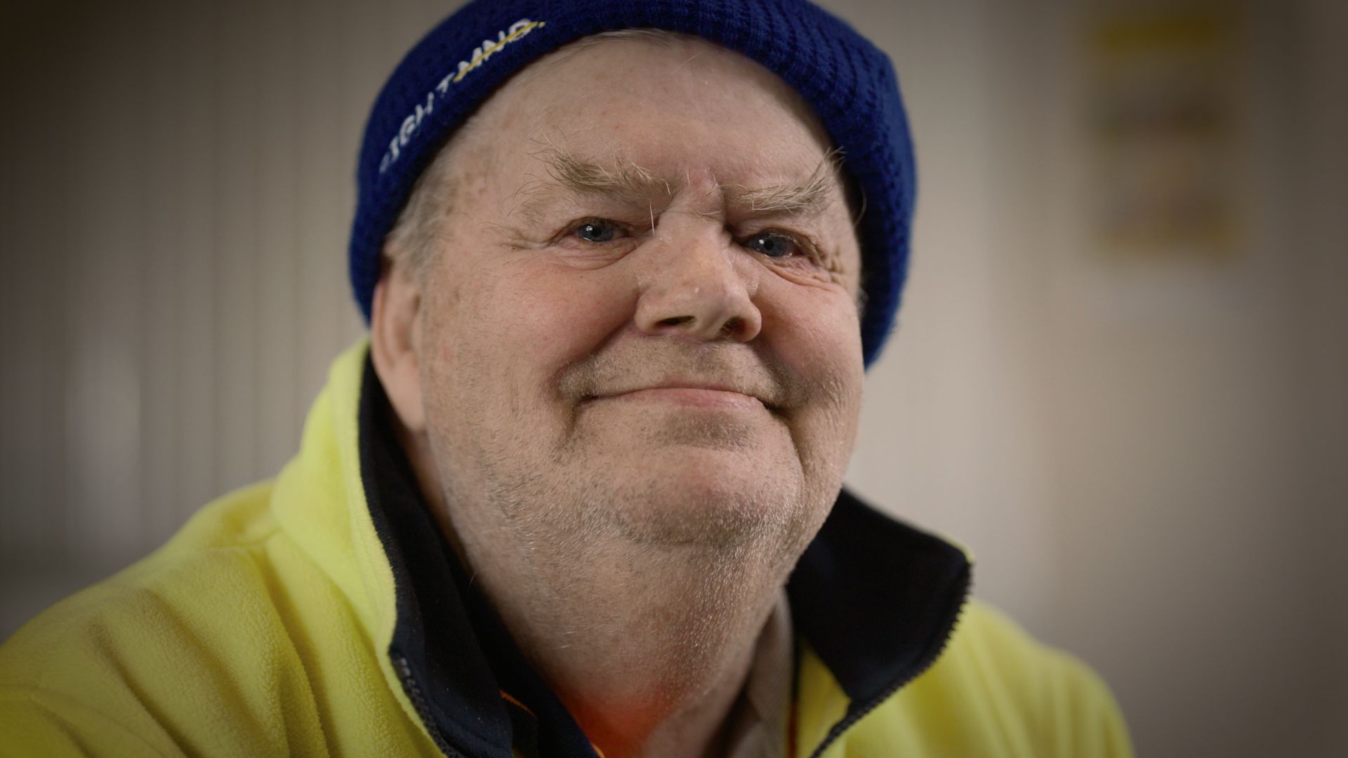 Headshot of man smiling at the camera, wearing a beanie and a high-vis jumper