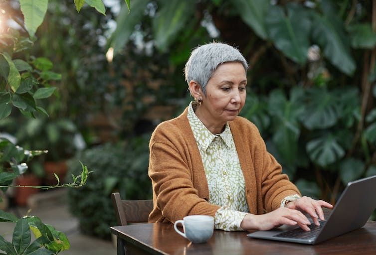 Woman working on her laptop in a lush backyard 
