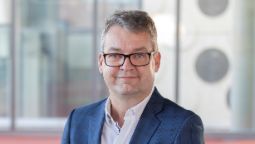 Man with short grey hair with glasses and blue jacket 
