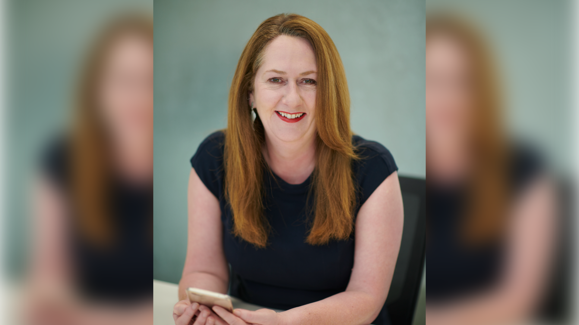 Swinburne alum and Associate Professor in Accounting at Swinburne, Dr Gráinne Oates is sitting at a desk smiling directly at the camera