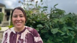 Woman standing outside in front of bushes smiling