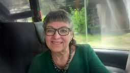 woman in green top with glasses smiling at the camera