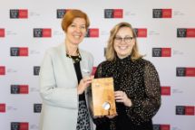 Early career researcher Dr Sara Webb and Vice Chancellor Professor Pascale Quester smile while holding a wood-crafted award