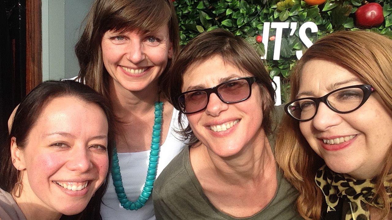 Four women smiling at camera at an event.
