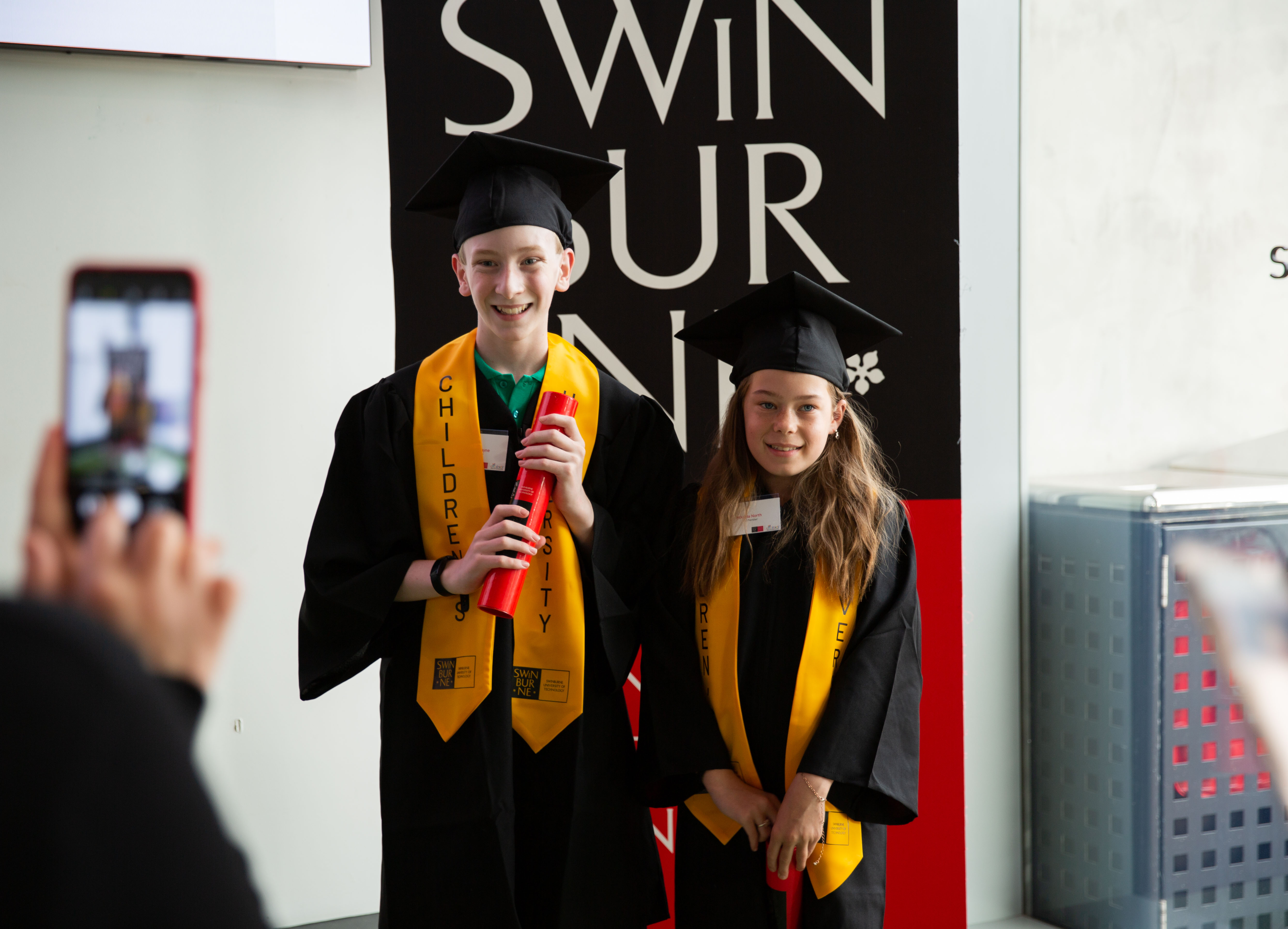 Two Children's University Swinburne members stand proudly with their graduation certificates. 