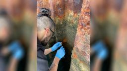 Man wearing latex gloves swabs rust on pylon