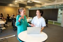 Swinburne Bachelor of Design/Bachelor of Business student Nasya Wu talking to a staff member about something on her laptop