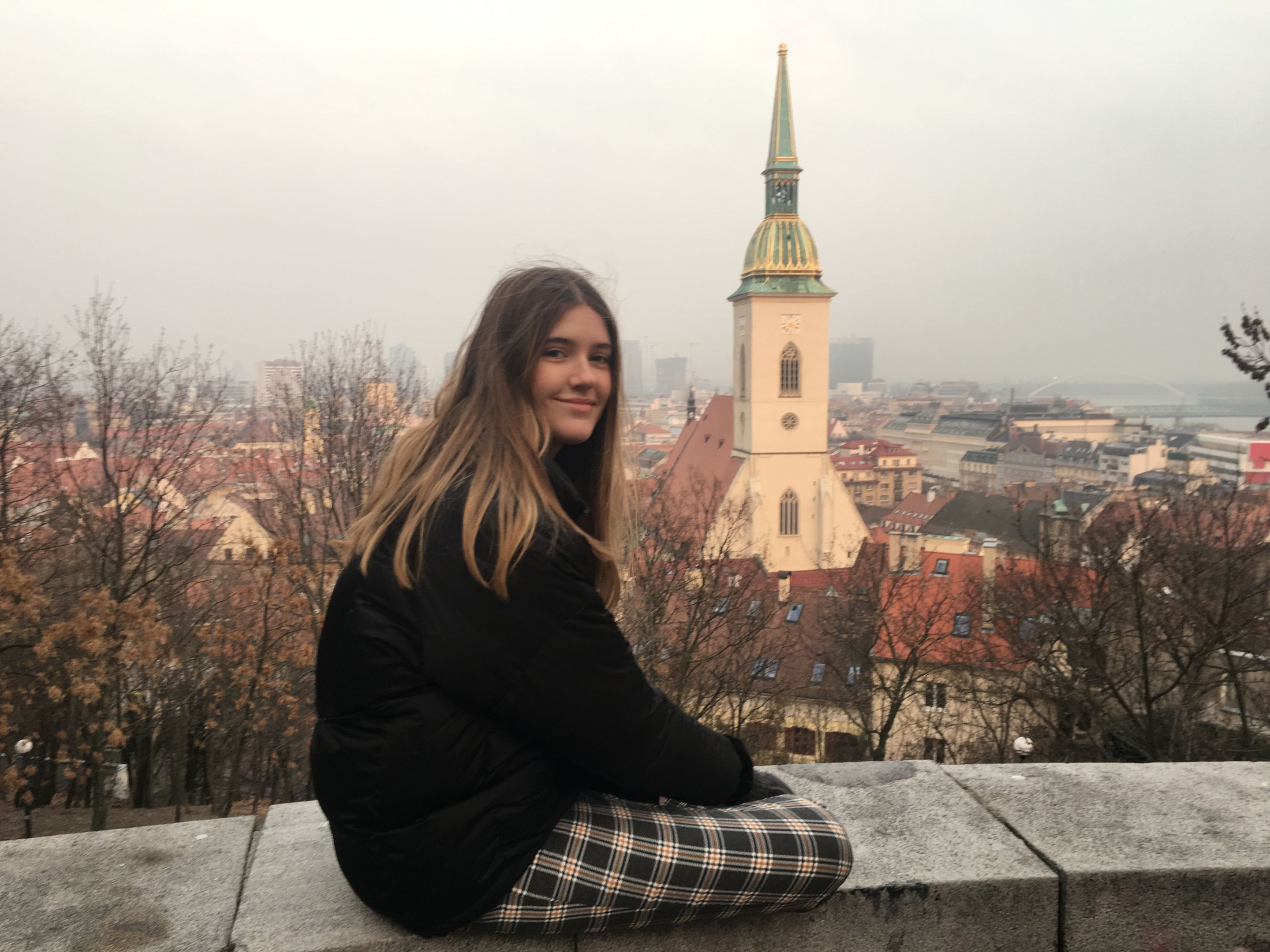 Student sitting on a ledge overlooking a European city