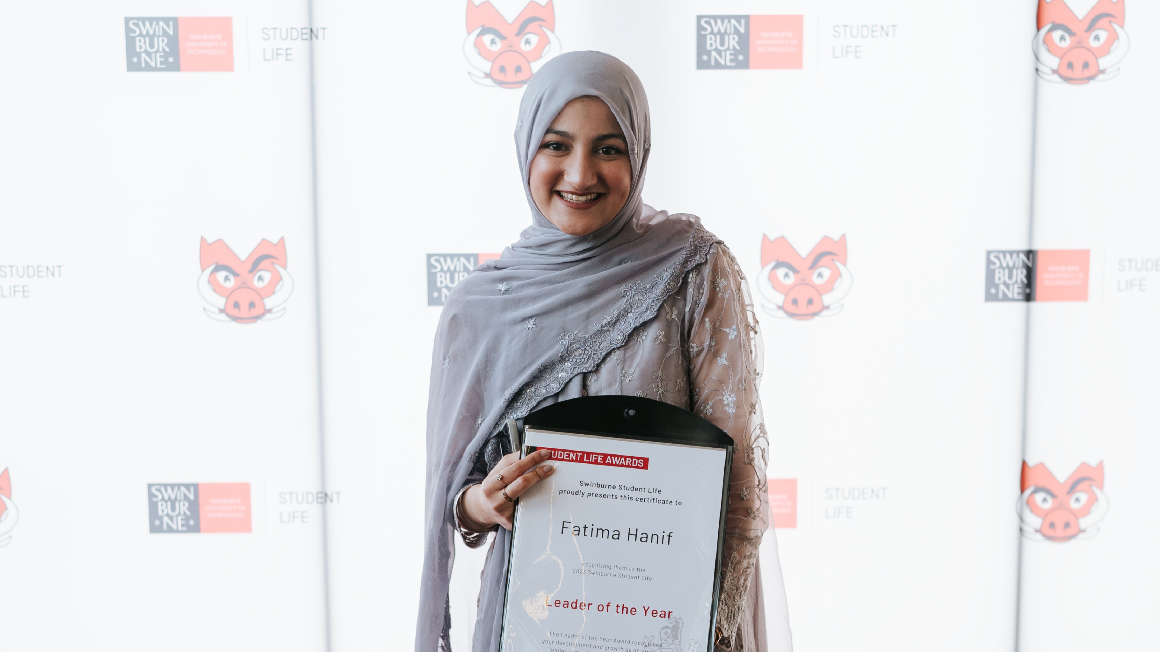 Bachelor of computer science graduate Fatima Hanif stands smiling holding a certificate for their award: leader of the year