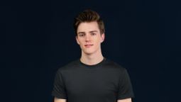 Young student standing face onto the camera wearing a black t-shirt and smiling with their mouth closed