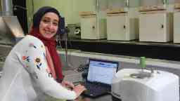 PhD student at her internship smiling with her laptop.