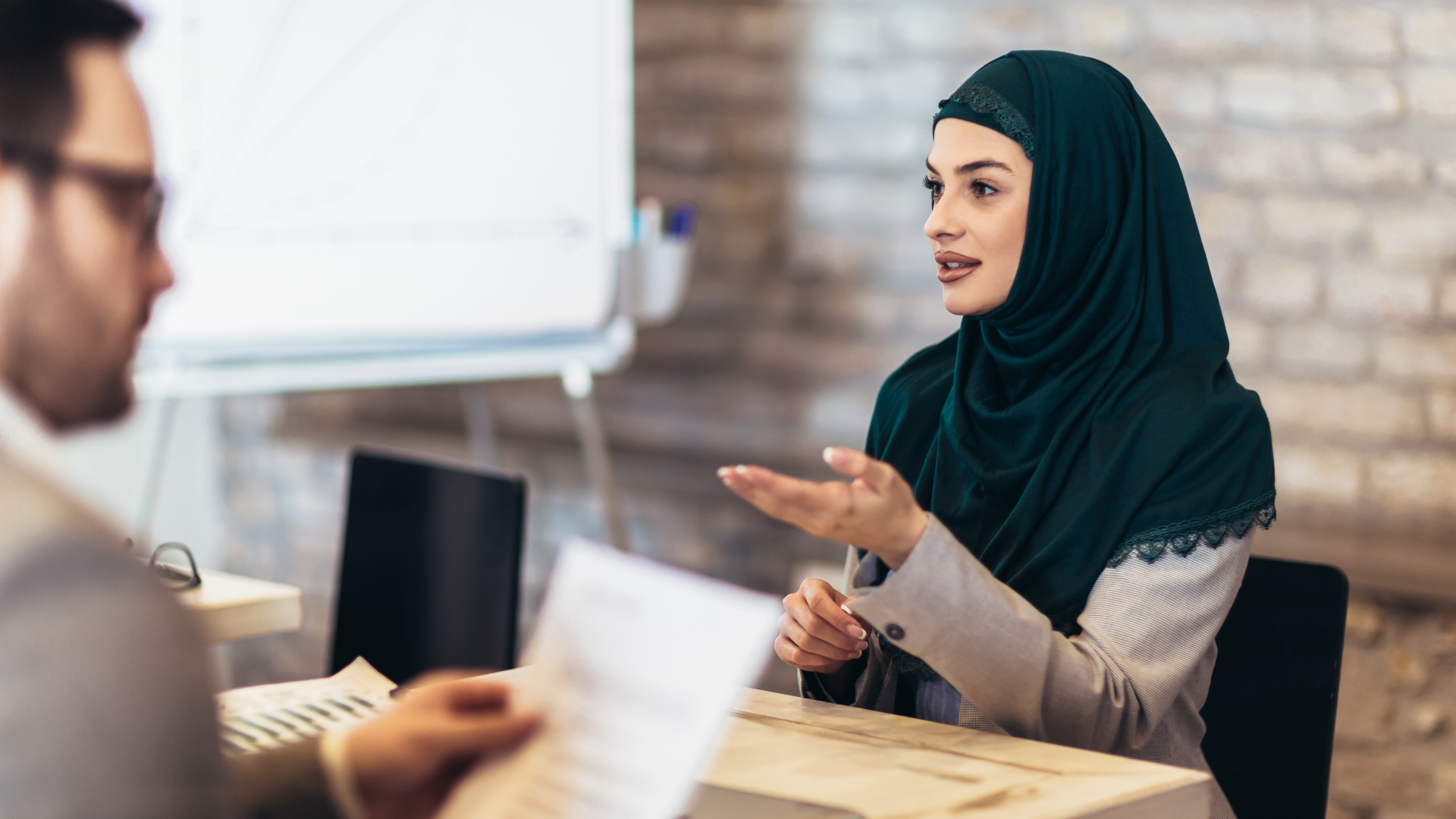 A female candidate (wearing a hijab) in a job interview in an office