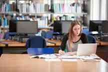 Female Student Working At Laptop In College Library