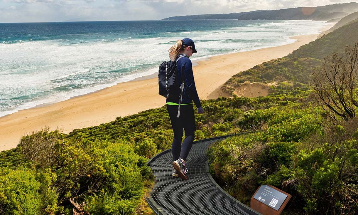 Woman walking on a coastal A modular boardwalk though foreshore shrubbery