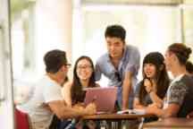 international students discuss a project and chat at a table