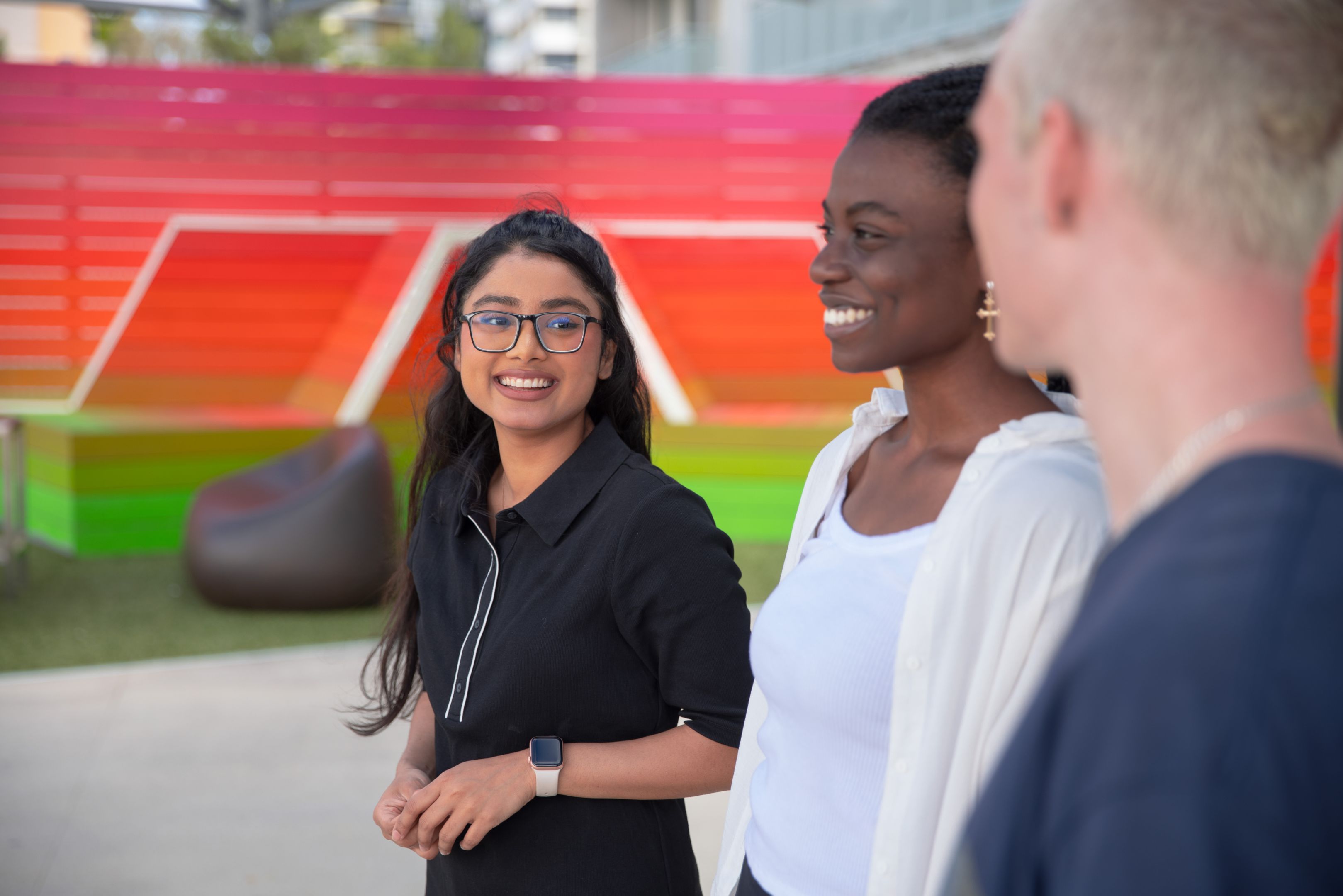 Three people standing, walking and talking (mid shot)