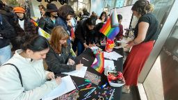 Students gather around a table with colourful craft supplies to create artworks