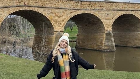 Student standing by a bridge
