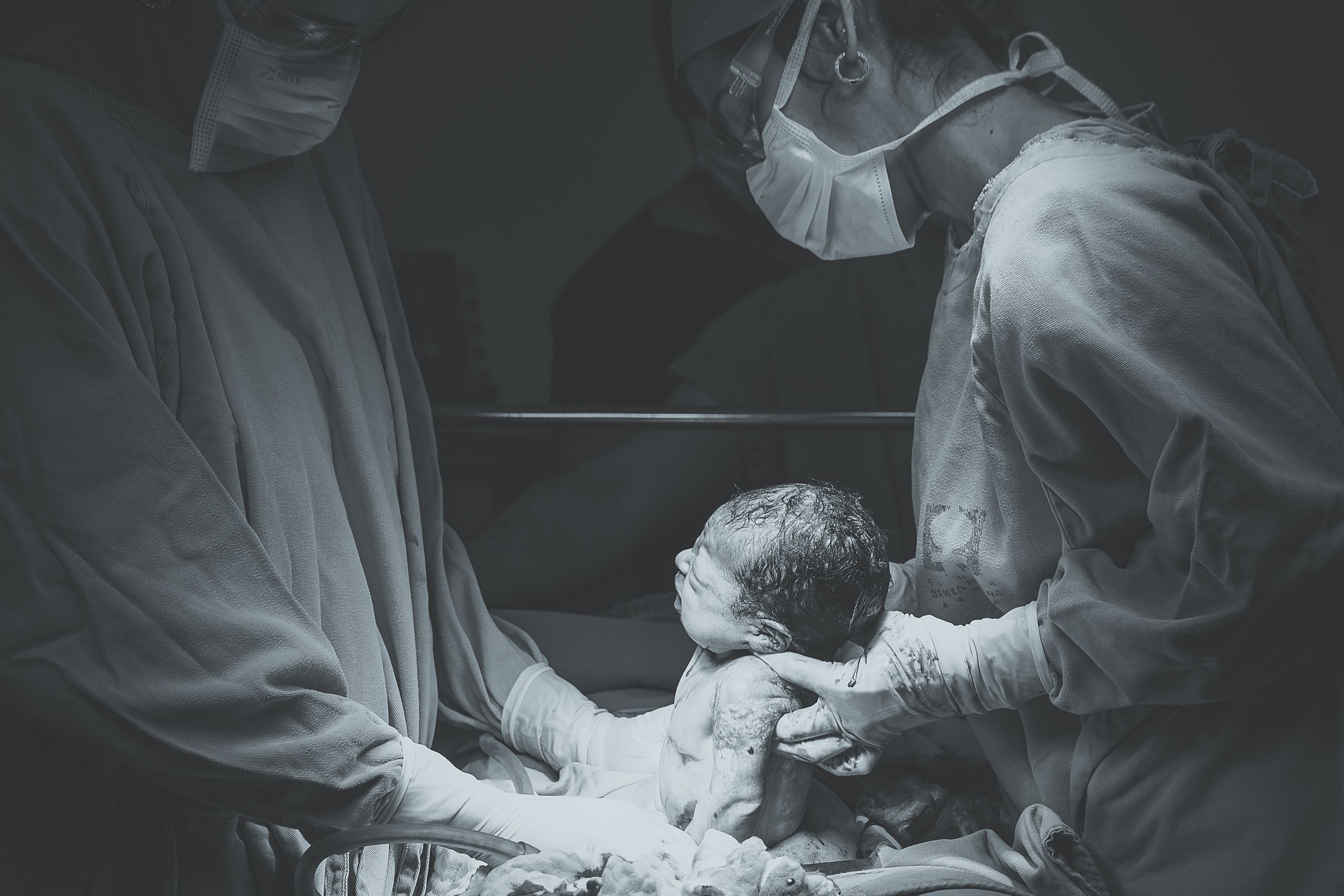 A black and white image of a newborn baby being held by nurses in a hospital