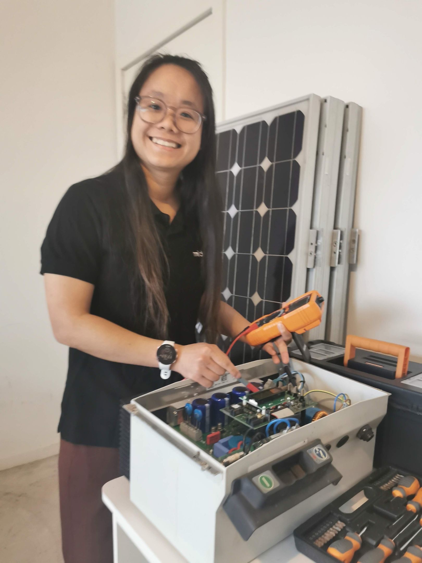 Amber Truong smiles as she works on solar panels in her garage