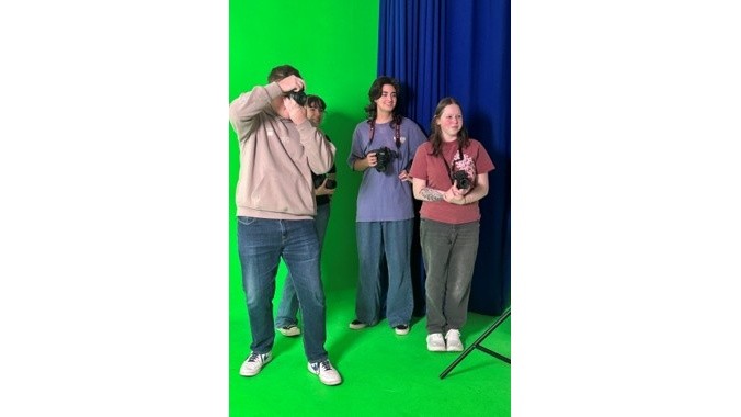 Students participating in a photography shoot using a green screen studio.