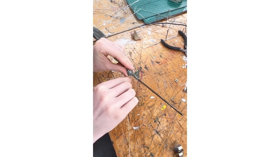 Student creating a wire sculpture in a workshop environment.