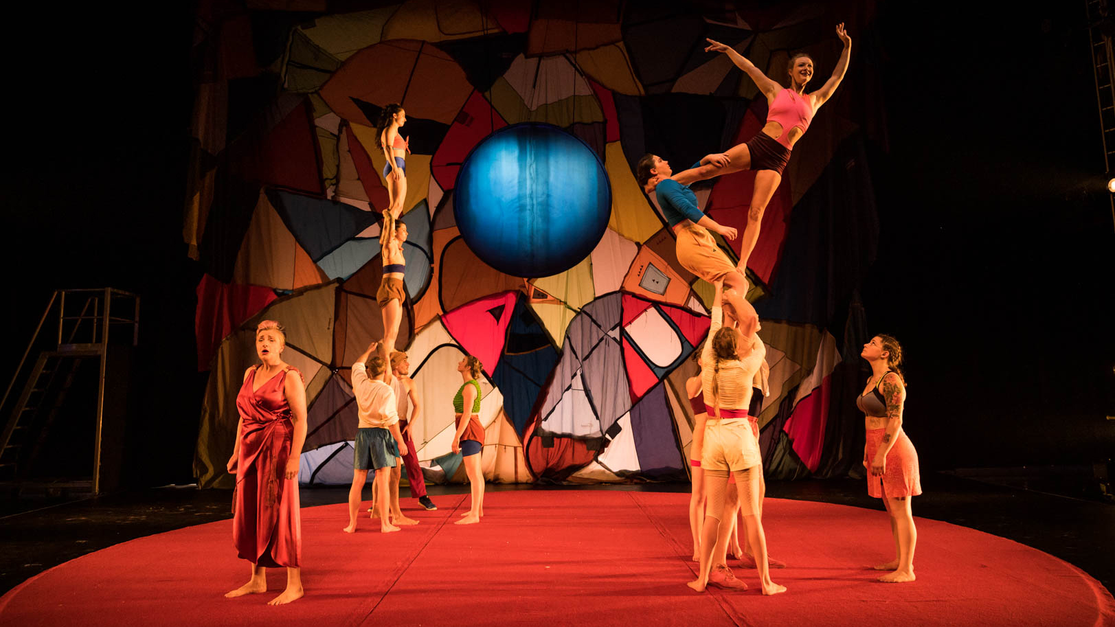 Acrobats perform on a stage wearing colourful clothing